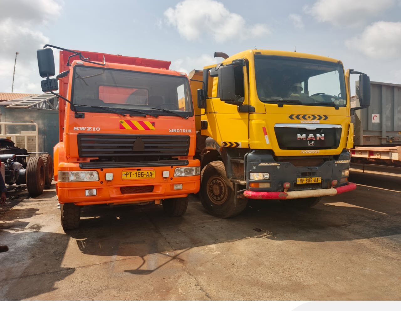 Camions MAN jaune et Sinotruk orange du parc matériel PSG