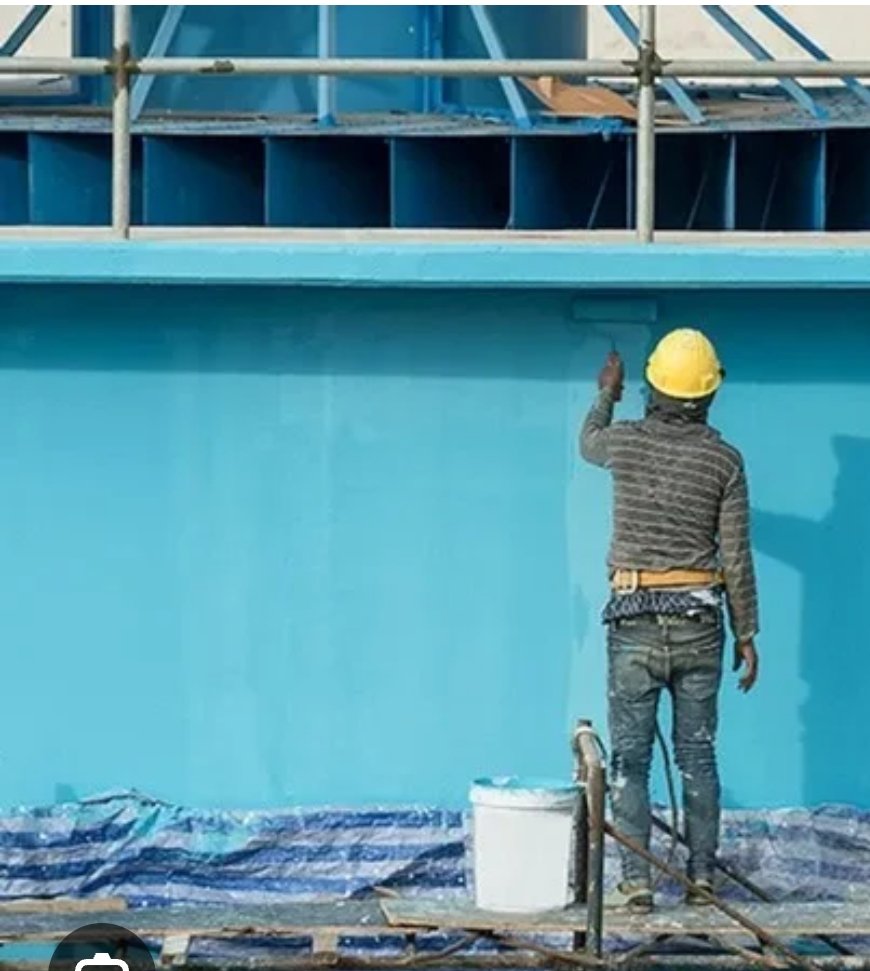 Peintre appliquant une peinture industrielle bleue sur la façade d'un bâtiment