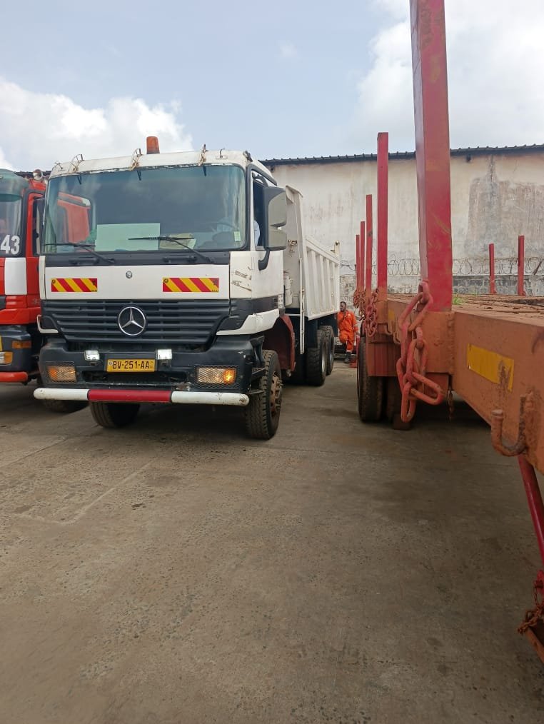 Camion Mercedes blanc stationné auprès d'une remorque plateau