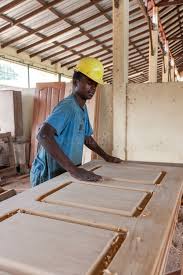 Ouvrier PSG en casque jaune assemblant des palettes en bois dans l'atelier